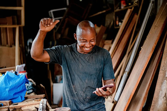 a man smiles while looking at his cell phone