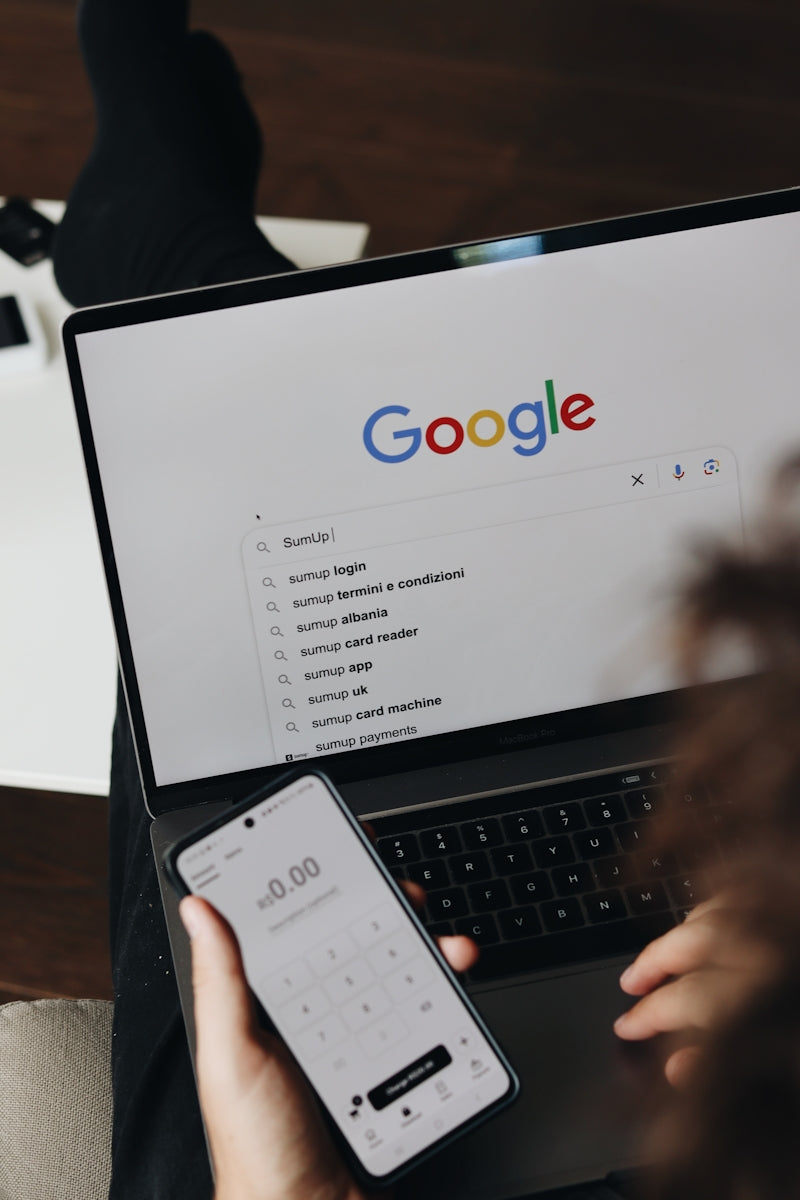 A person holding a cell phone and a laptop